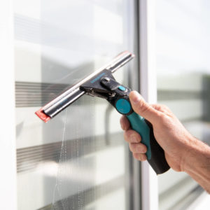 Window cleaner using a squeegee to clean a commercial window in South Manchester
