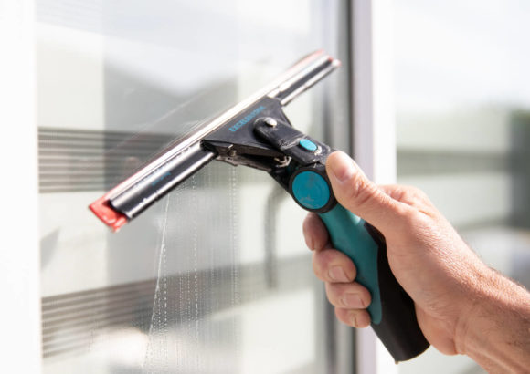 Window cleaner using a squeegee to clean a commercial window in South Manchester